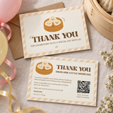 Front and back of the little dumpling 1st birthday thank you card on a linen tablecloth with a kraft envelope and balloons