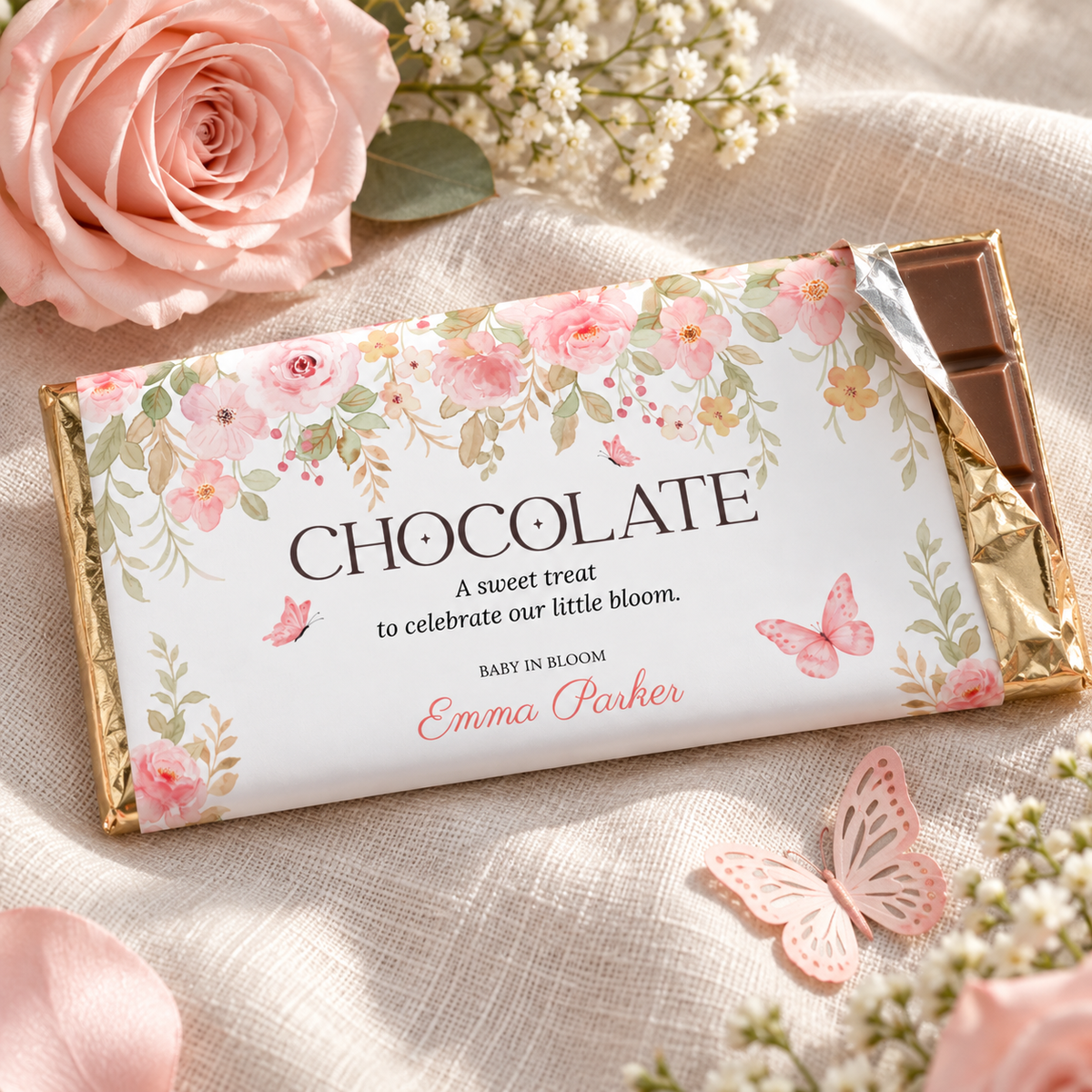 Close-up of a pink floral baby shower chocolate bar wrapper with the foil peeled back