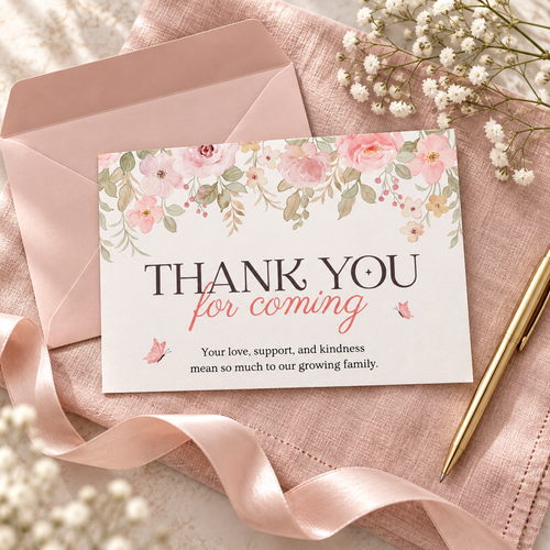 Flat lay of a pink floral baby shower thank you card with blush envelope and gold pen