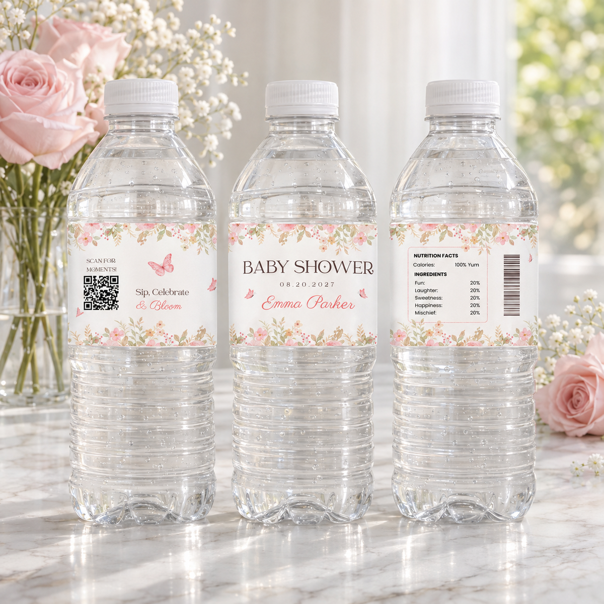 Three water bottles with baby in bloom labels on a marble table with pink roses