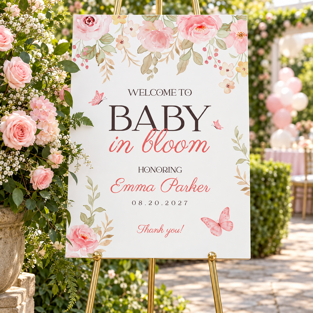 Baby in bloom baby shower welcome sign on a gold easel next to pink roses