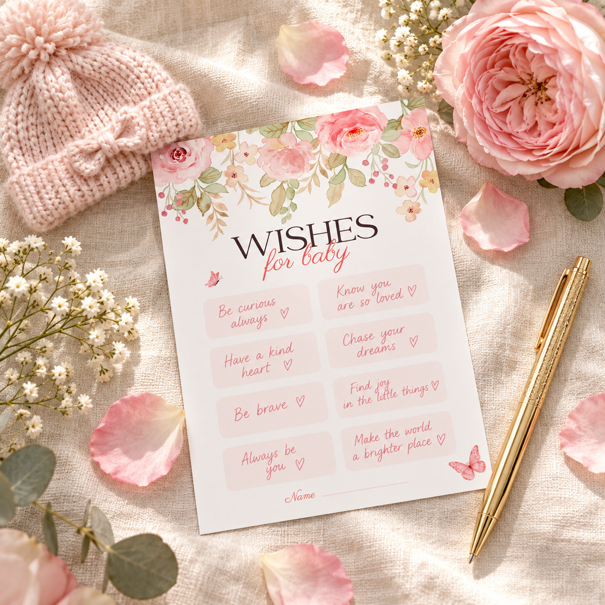 Filled-in pink floral wishes for baby card with a knitted baby hat and gold pen