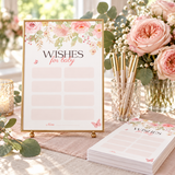 Baby in bloom wishes for baby card in a gold frame on a shower table with roses and pens