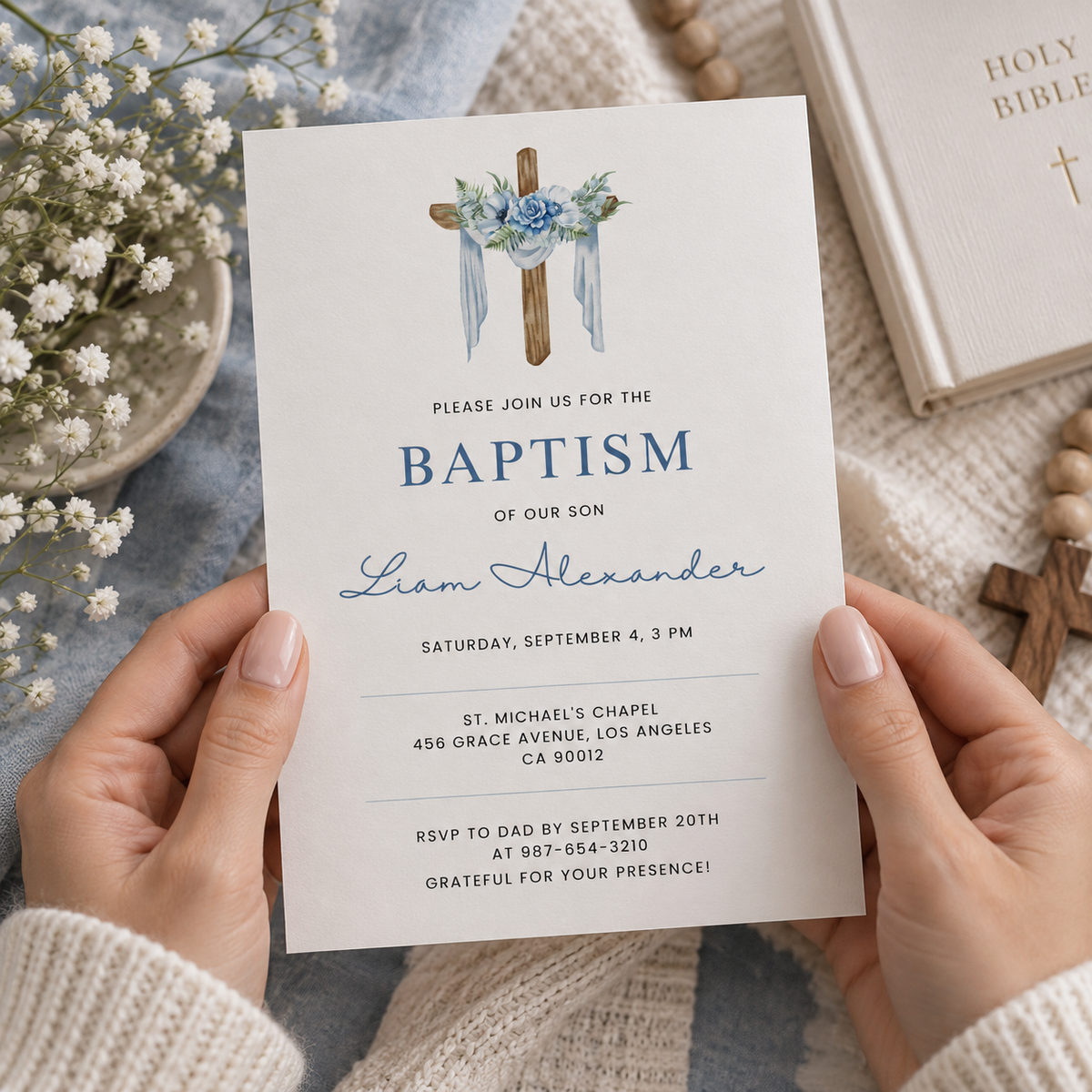 Baptism invitation with a draped wooden cross and blue roses, styled on a table