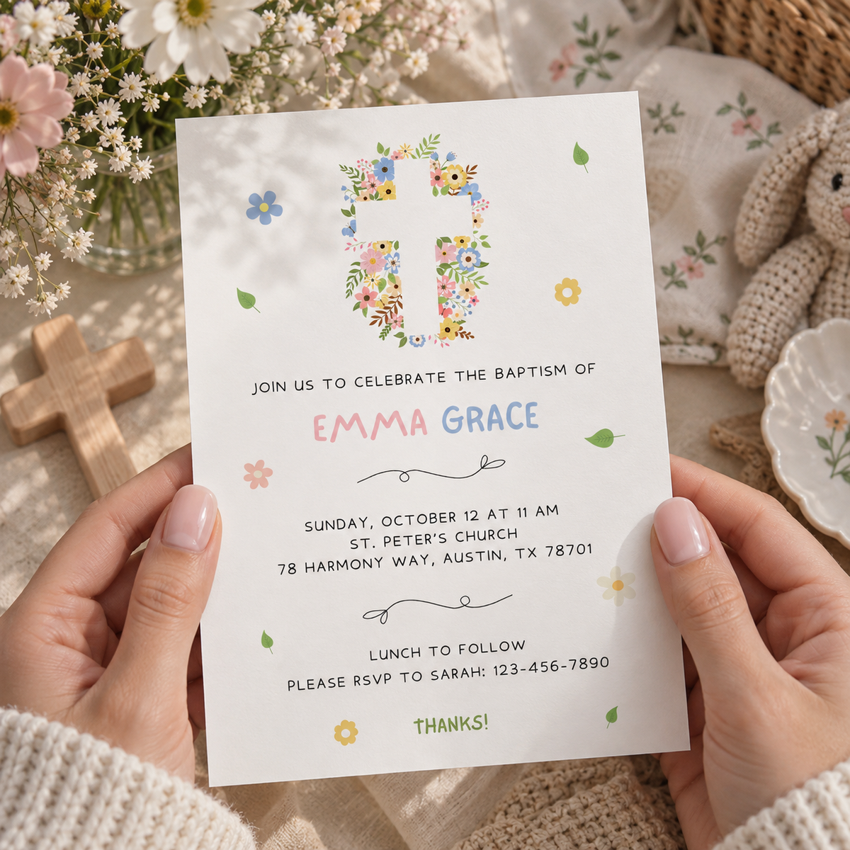 Girl baptism invitation with a cross made of pink and blue flowers, styled on a table