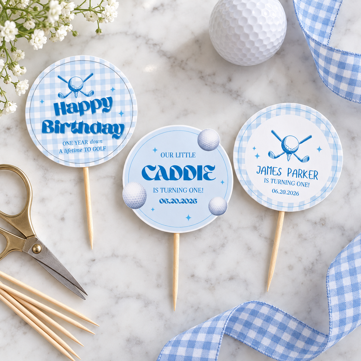 Flat lay of printed golf hole in one cupcake toppers on toothpicks with scissors and a golf ball