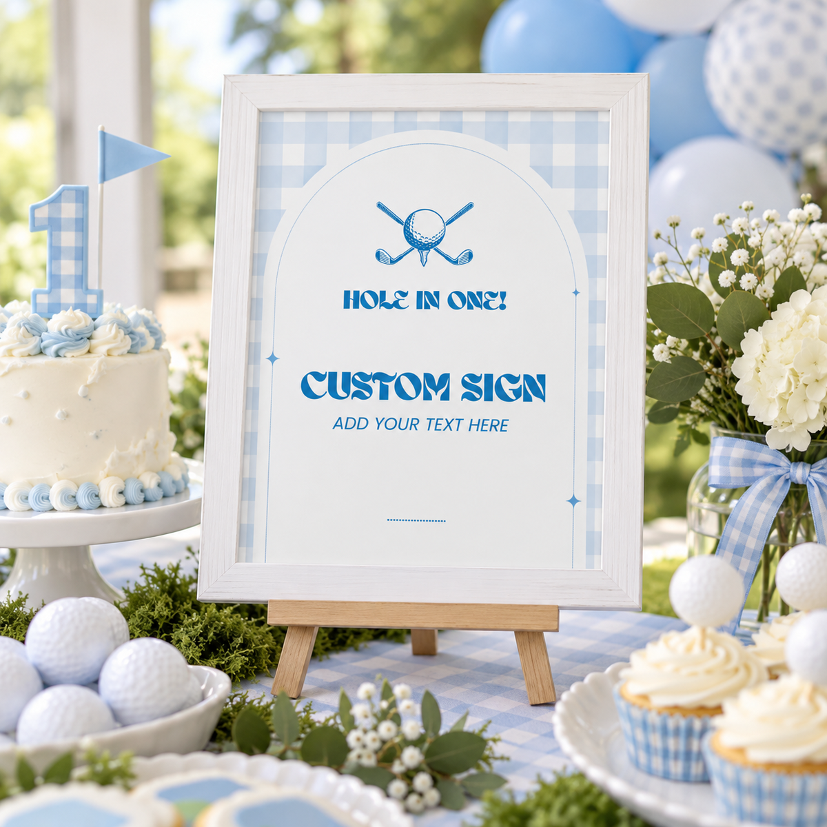 Golf hole in one 1st birthday custom sign in a white frame on an easel at a blue gingham dessert table