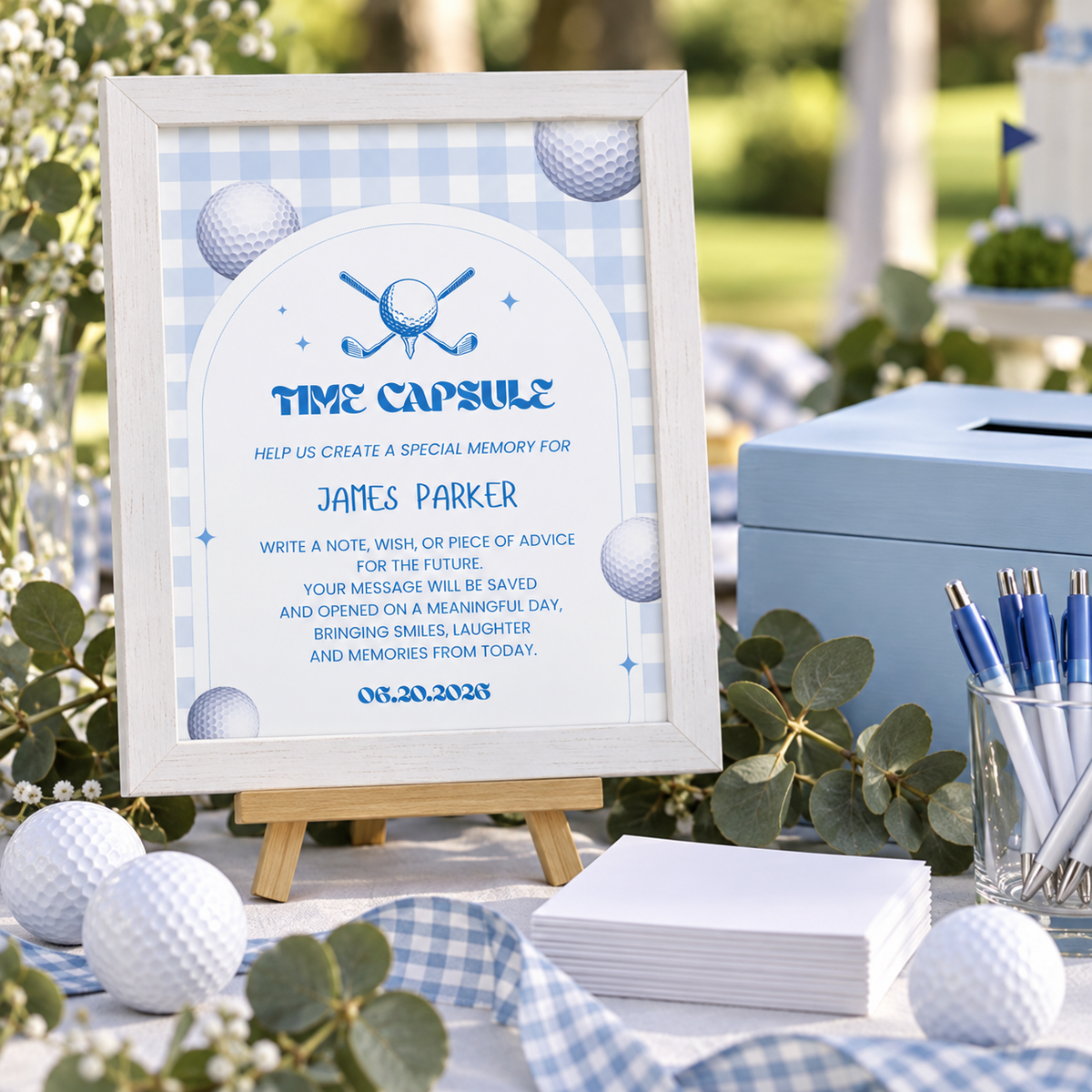 Golf hole in one 1st birthday time capsule sign in a white frame next to a blue keepsake box and note cards