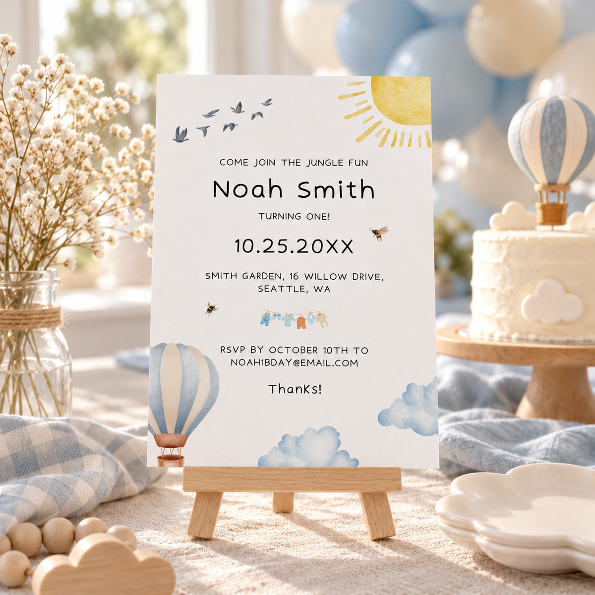 Up up and away first birthday party table with the printed hot air balloon invitation on an easel and a balloon cake