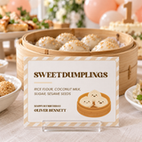 Little dumpling food label in an acrylic stand in front of a steamer of sesame dumplings