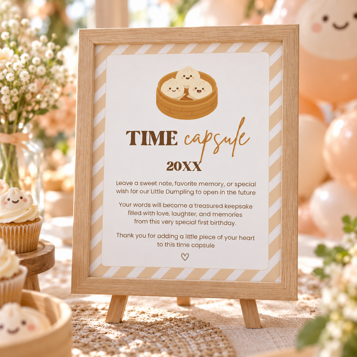 Close-up of the dumpling time capsule sign on an easel with peach balloons and dumpling cupcakes