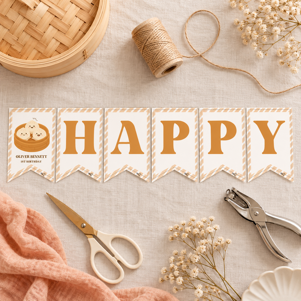 Flat lay of the printed little dumpling birthday pennants with twine, scissors and a hole punch