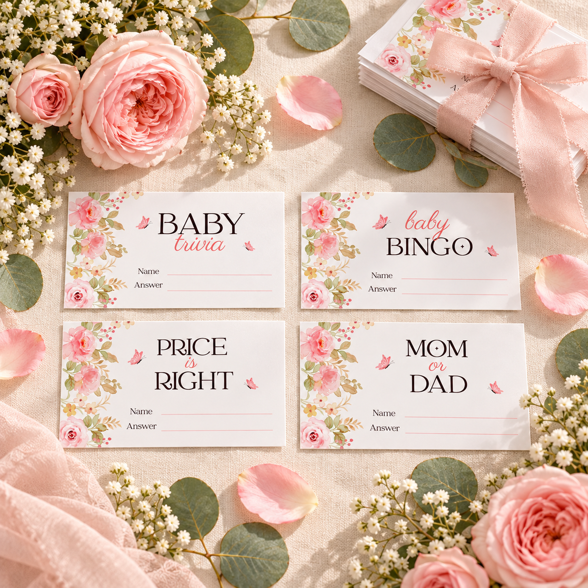Flat lay of four pink floral baby shower game tickets with rose petals