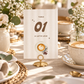 Baby Is Brewing coffee baby shower table number in a gold stand on a brunch table