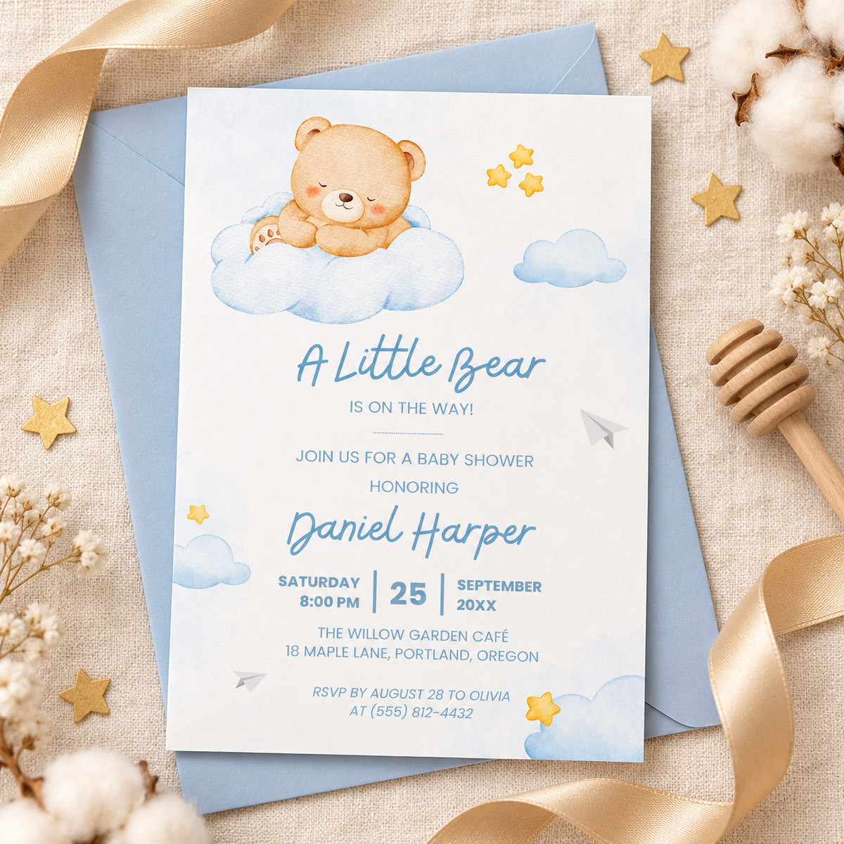 Teddy bear baby shower invitation flat lay with blue envelope and honey ribbons