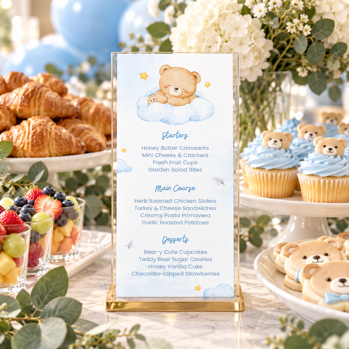 Little Bear teddy bear menu in a stand on a baby shower buffet with croissants and cupcakes