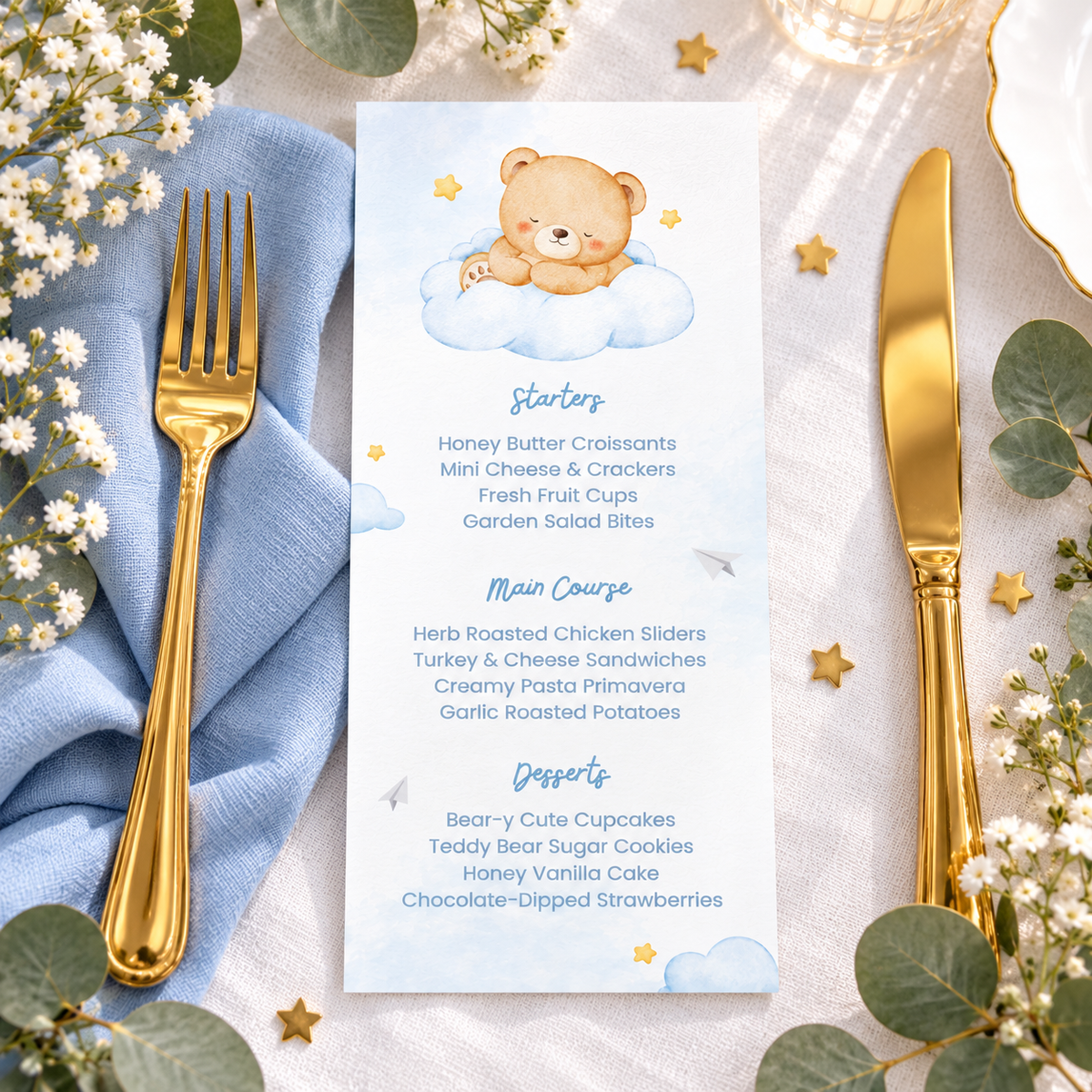 Flat lay of the Little Bear baby shower menu card with a blue napkin and gold cutlery