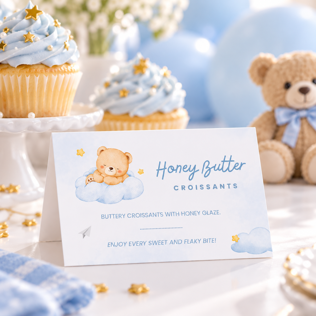 Close-up of a Little Bear food tent card next to blue frosted cupcakes