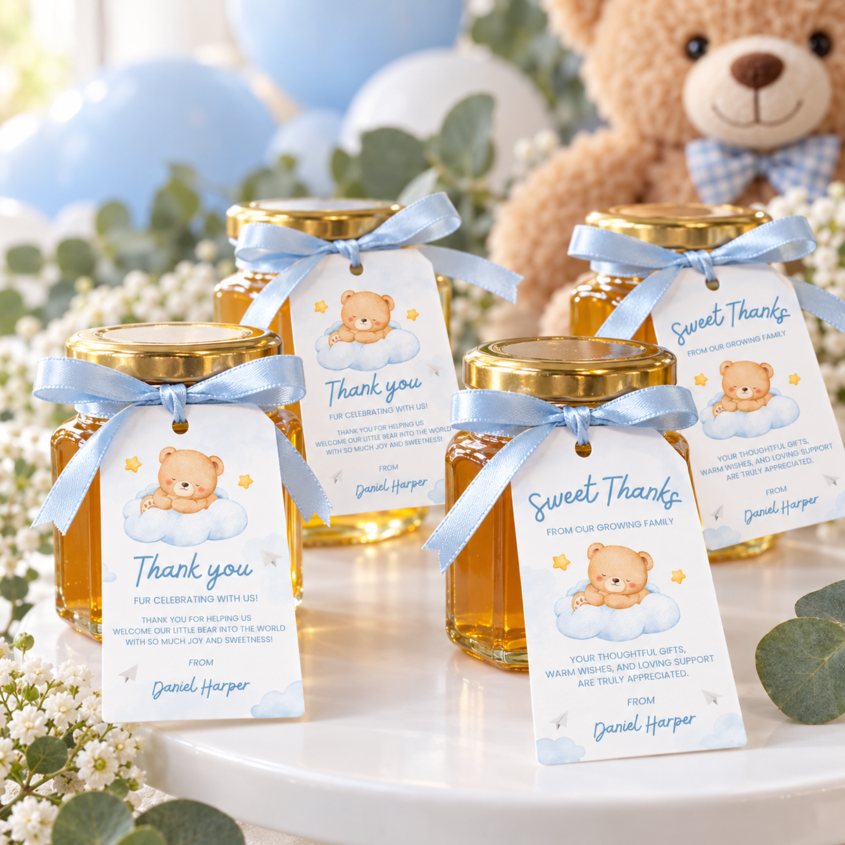 Little Bear baby shower favor tags tied with blue ribbon to honey jar favors next to a teddy bear