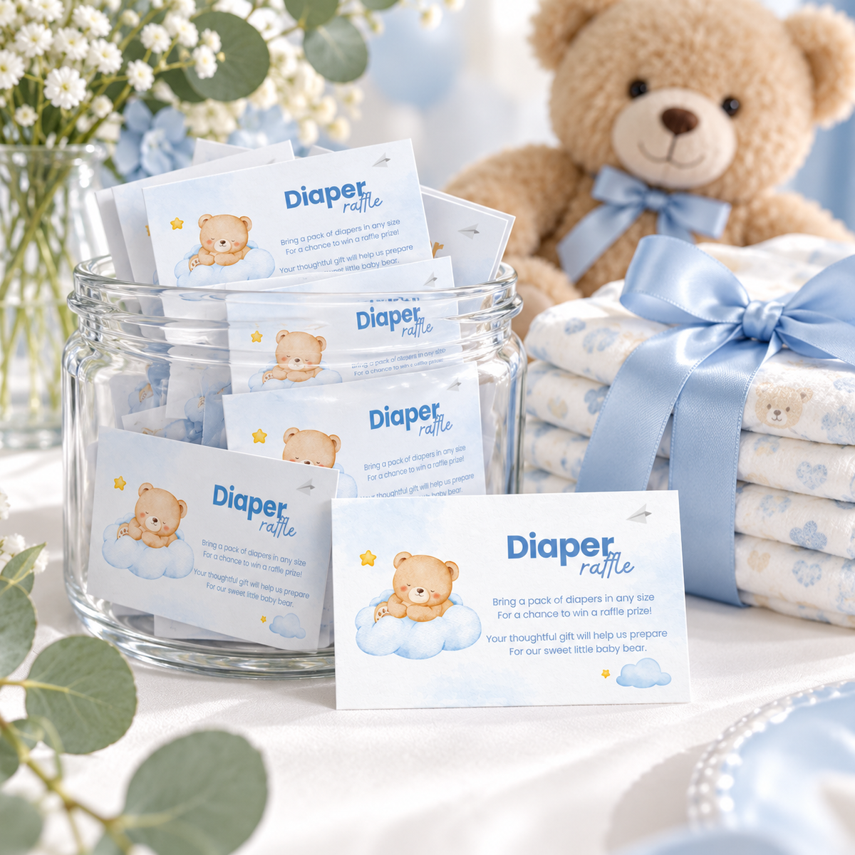 Jar of Little Bear diaper raffle cards next to a stack of diapers with a blue bow and a teddy bear