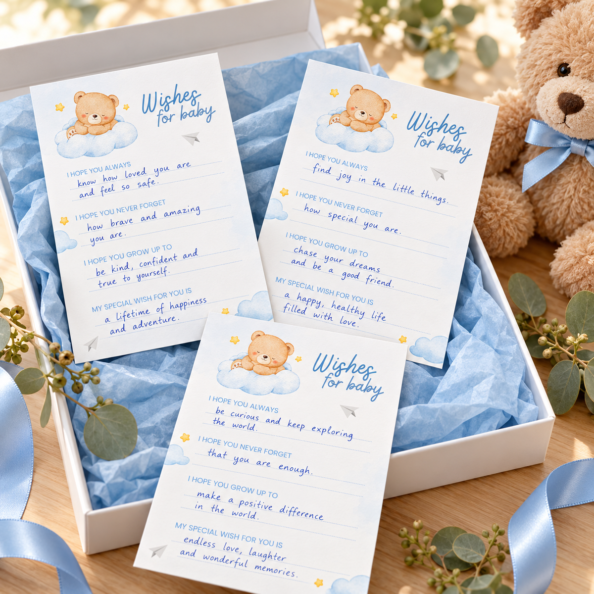 Three Little Bear wishes for baby cards filled in with handwritten wishes in a white keepsake box with blue tissue paper and a teddy bear