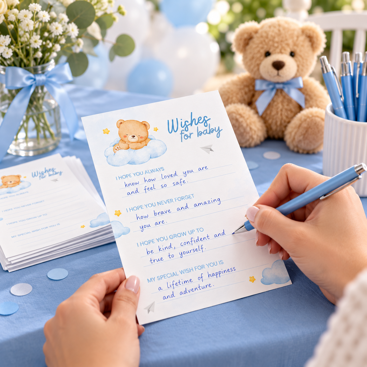 Guest writing a wish on a Little Bear teddy bear wishes card with a blue pen at a blue baby shower table