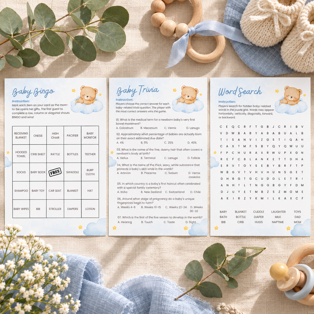 Flat lay of three Little Bear baby shower game cards on linen with eucalyptus
