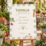 Locally Grown baby shower welcome sign on a wooden easel at a farmers market style shower entrance with produce crates