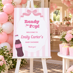 Ready To Pop baby shower welcome sign on an easel at a pink shower entrance with balloons and striped popcorn boxes