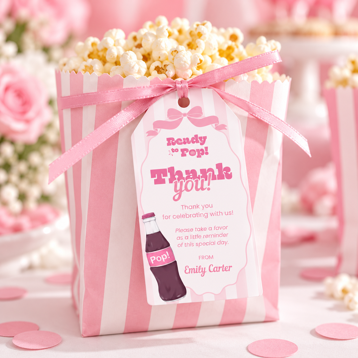 Close-up of a Ready To Pop thank you favor tag on a pink striped popcorn bag