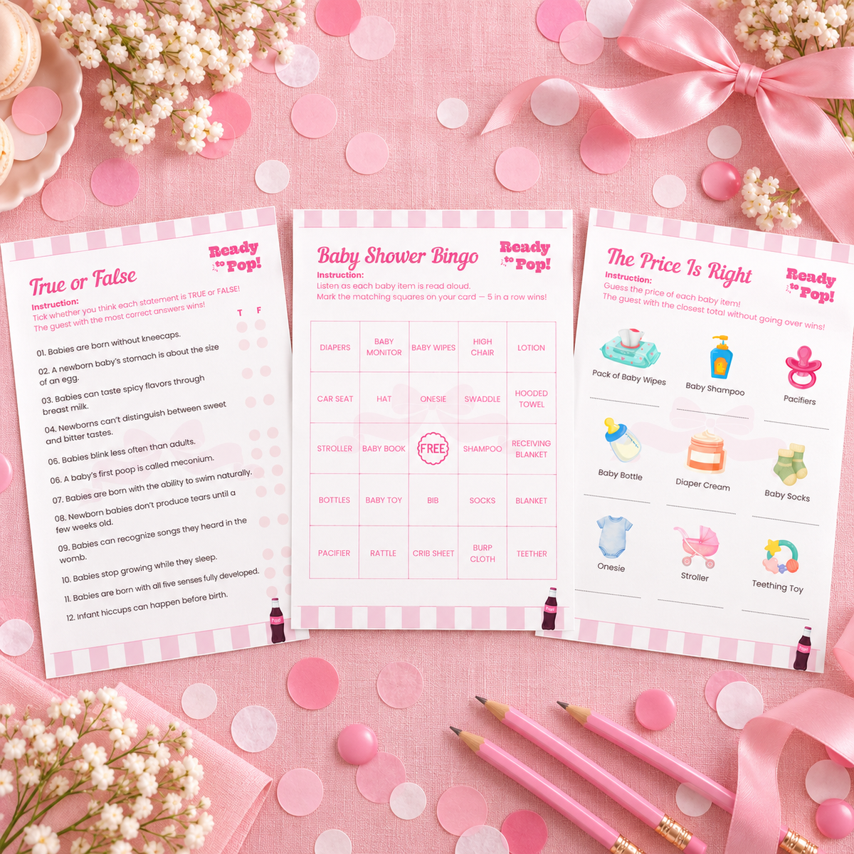 Flat lay of three Ready To Pop baby shower game cards with pink confetti and a satin bow