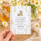 Hand holding the Classic Honey Bear baby shower invitation in front of honey jars and daisies