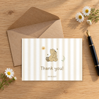 Classic Honey Bear baby shower thank you card on a wooden desk with a kraft envelope, fountain pen and daisies
