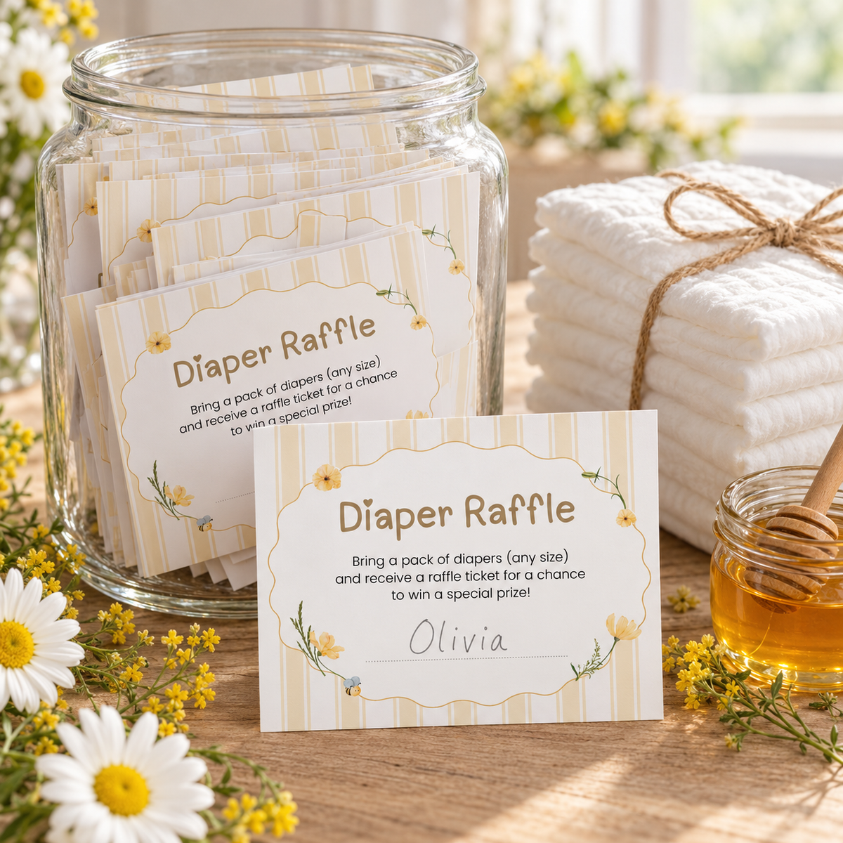 Glass raffle jar filled with Classic Honey Bear diaper raffle cards next to a stack of diapers tied with twine